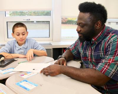 Para Educator at table helping elementary student